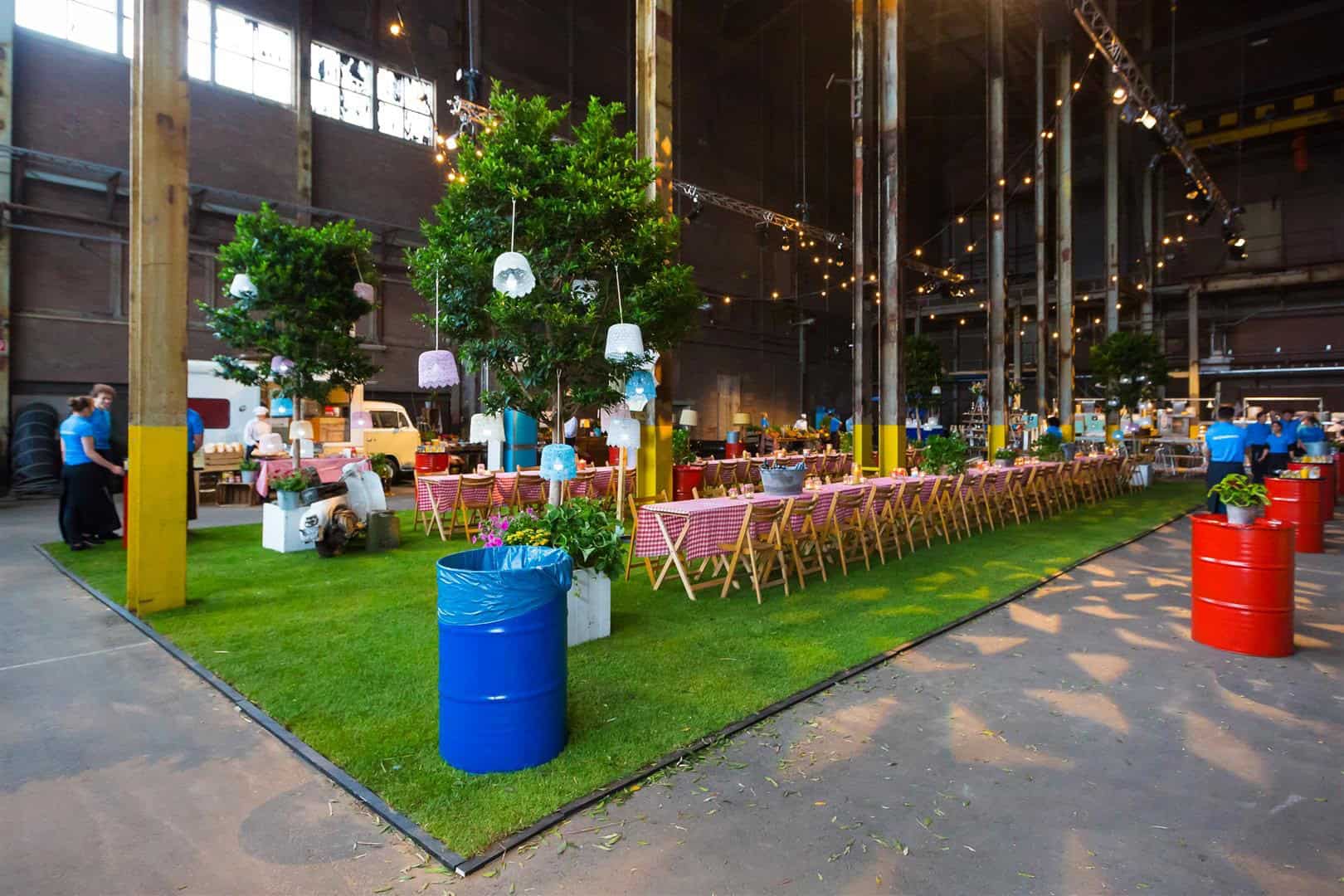 Gezellig feest met lange tafels, groene planten en sfeervolle verlichting.