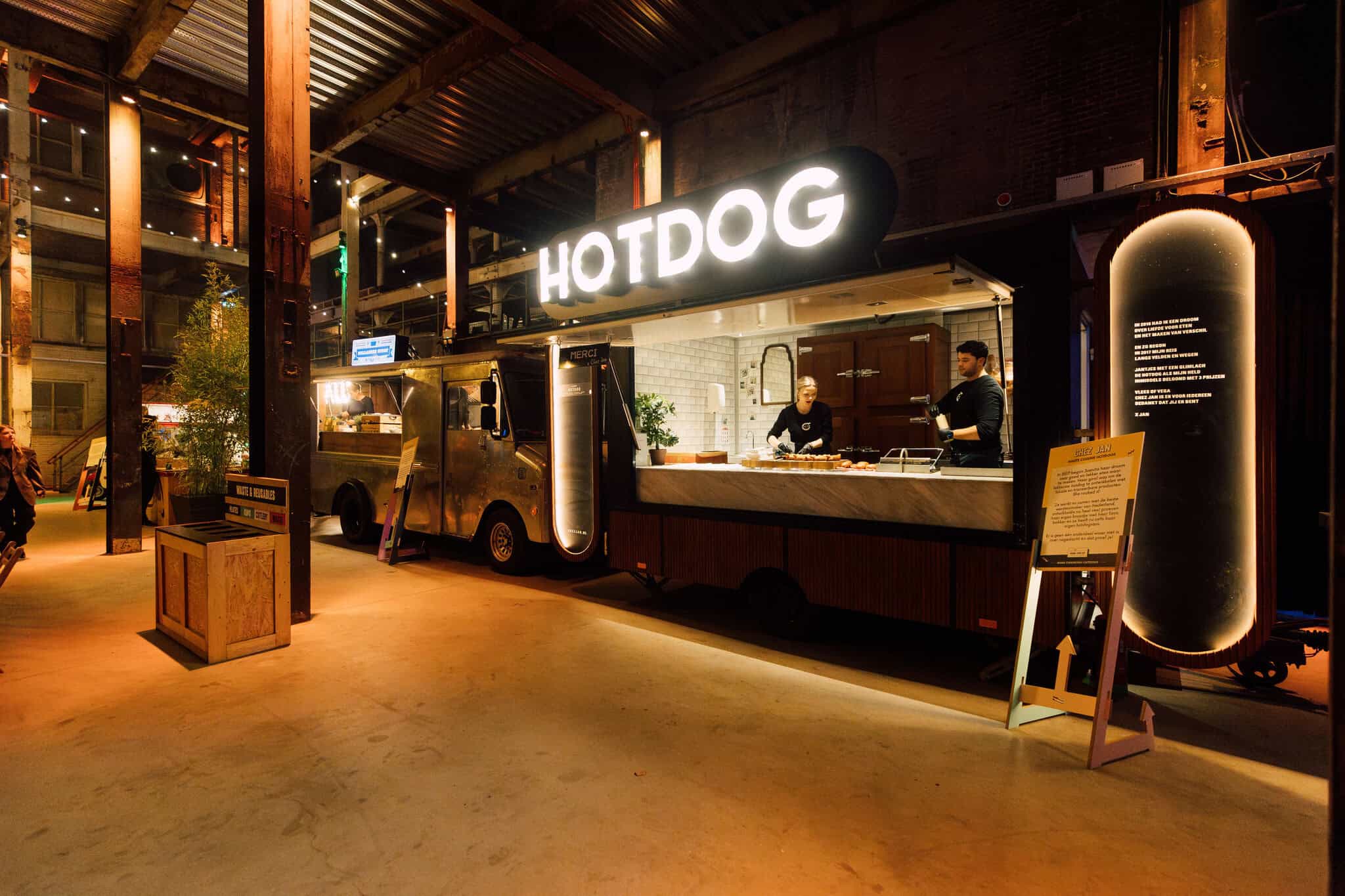Food truck serving hotdogs at night with illuminated sign "HOTDOG".