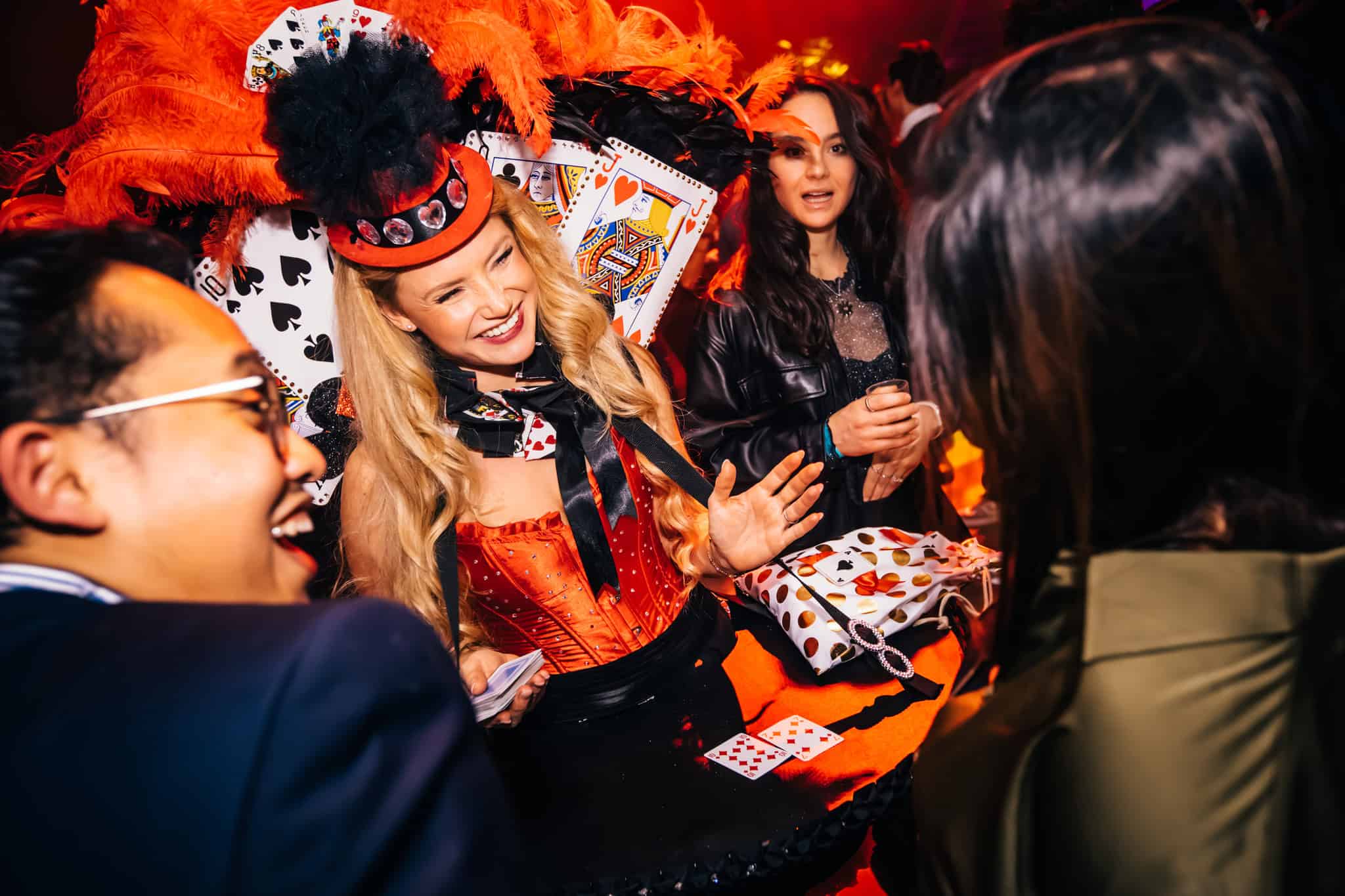 Vrolijke vrouw in kleurrijk kostuum met kaarten en veren op een evenement.