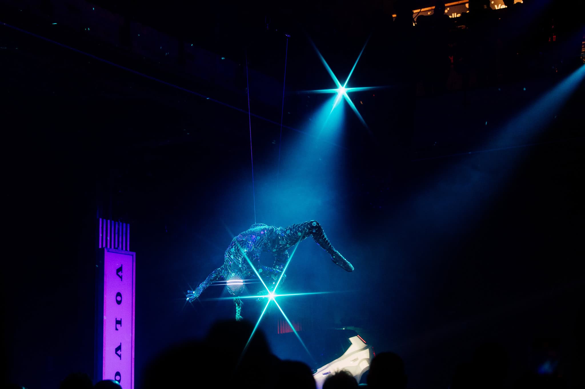 Man in kleurrijk feestkostuum met masker en bril op outdoor festival.