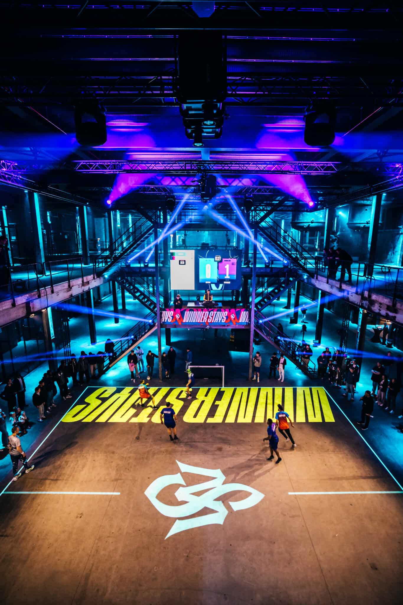 Sportevenement in een grote, moderne zaal met kleurrijke verlichting en een sportveld.