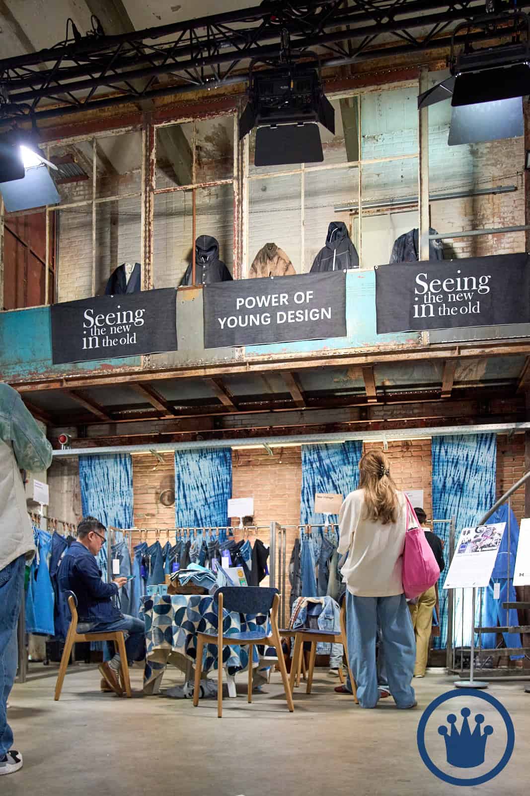 Interieur van een modewinkel met klanten en kledingrekken.